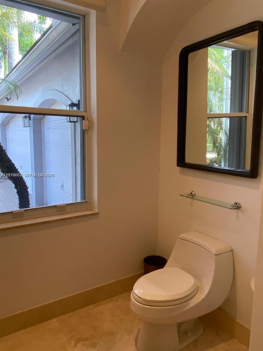 Tray ceiling with recessed lighting, wood-finish flooring, arched entryway, and large windows with exterior pool access