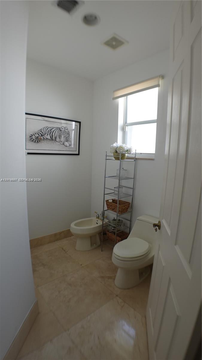 Bathroom featuring a vanity with integrated sink and stone-finish countertop, white cabinetry, framed mirror, and a shower stall with glass enclosure