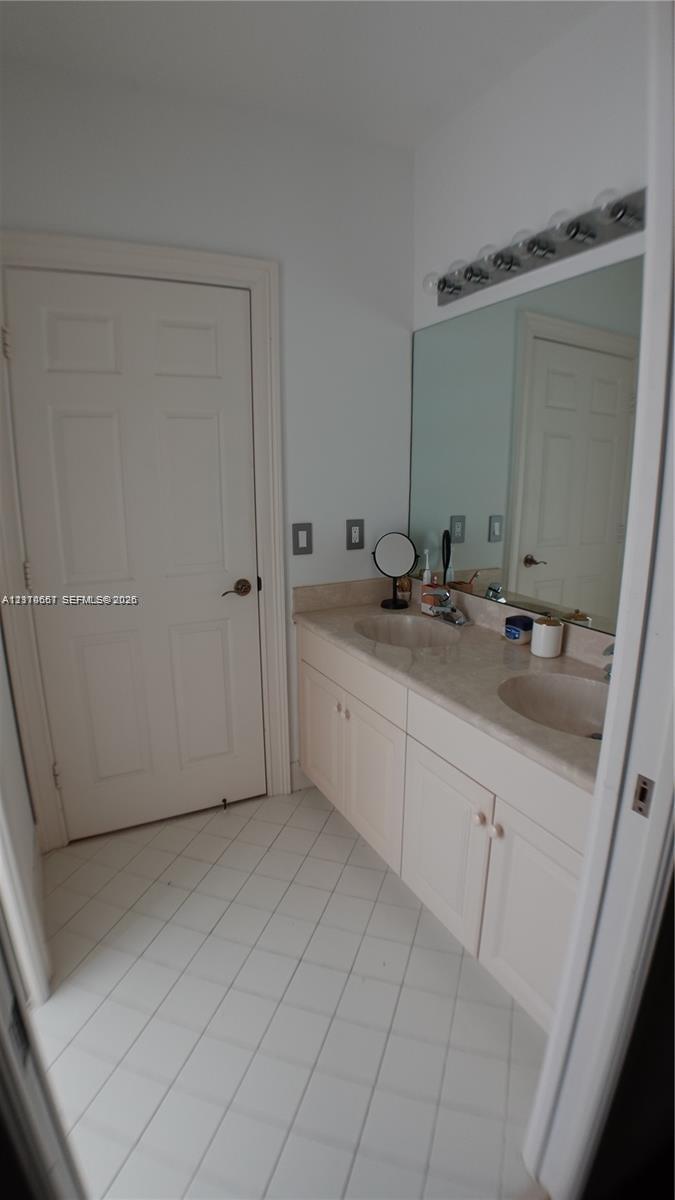 Laundry area featuring flat-panel wood-finish cabinetry, a white countertop, an undermount stainless steel sink, and a high-arc matte black faucet