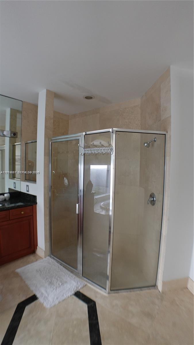 Restroom featuring stone-finish flooring, a wall-mounted rectangular mirror with a dark frame, a glass shelf, and a high-profile one-piece toilet