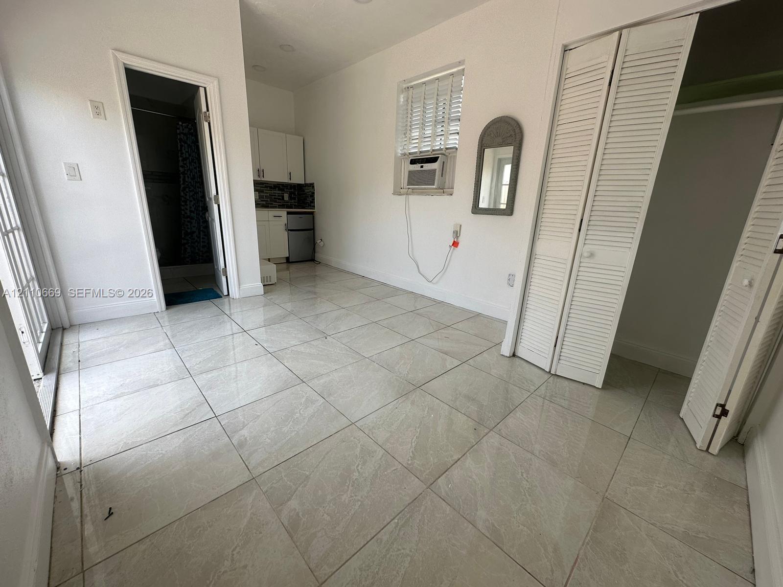 Neutral tile flooring, white cabinetry, louvered closet doors, and recessed ceiling lighting