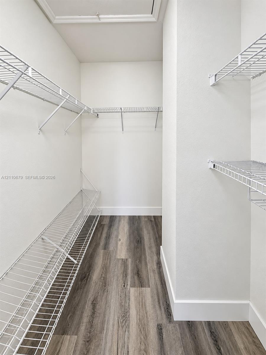 Walk-in storage space featuring wood-finish flooring and multi-level white wire shelving