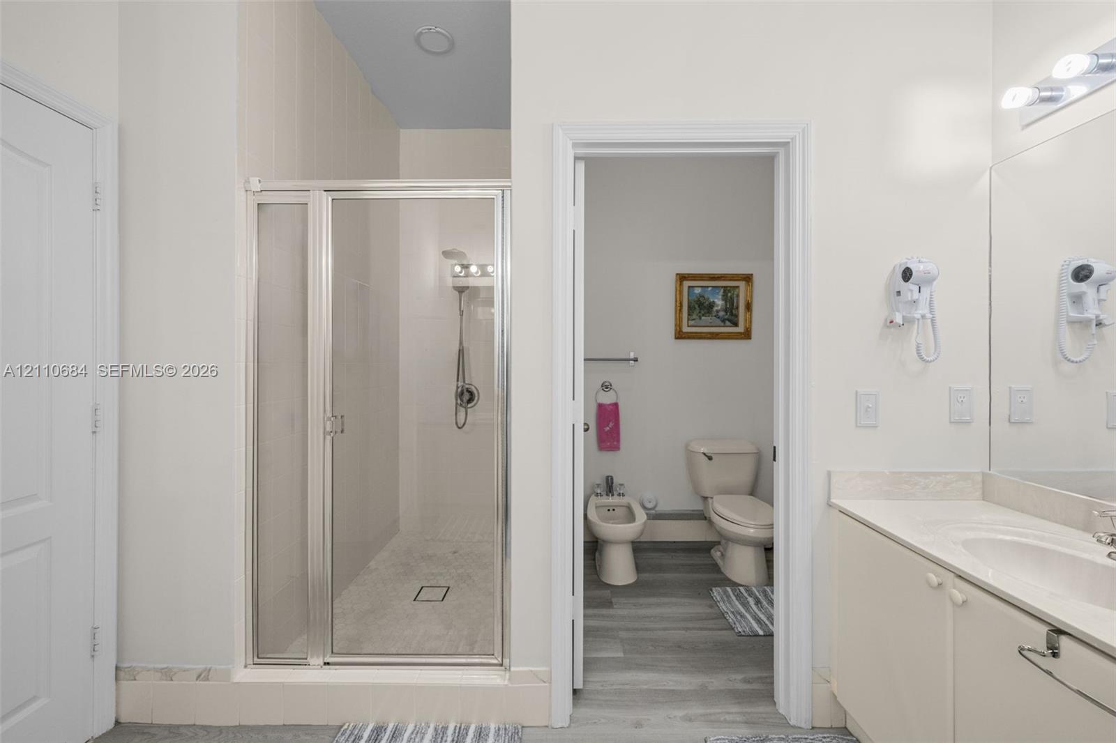walk-in shower with metal-framed glass enclosure, vanity with integrated basin, bidet, toilet