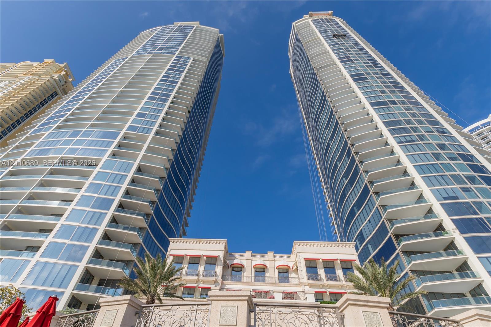 High-rise architectural design featuring glass facades, multiple private balconies, and stone-detailing base structure