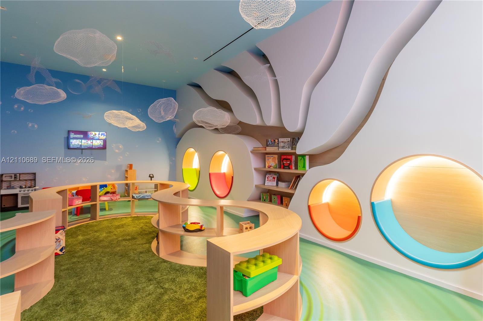 Custom sculptural wall molding with integrated circular niches, tiered curved wood-finish shelving, recessed accent lighting, and cloud-patterned ceiling fixtures