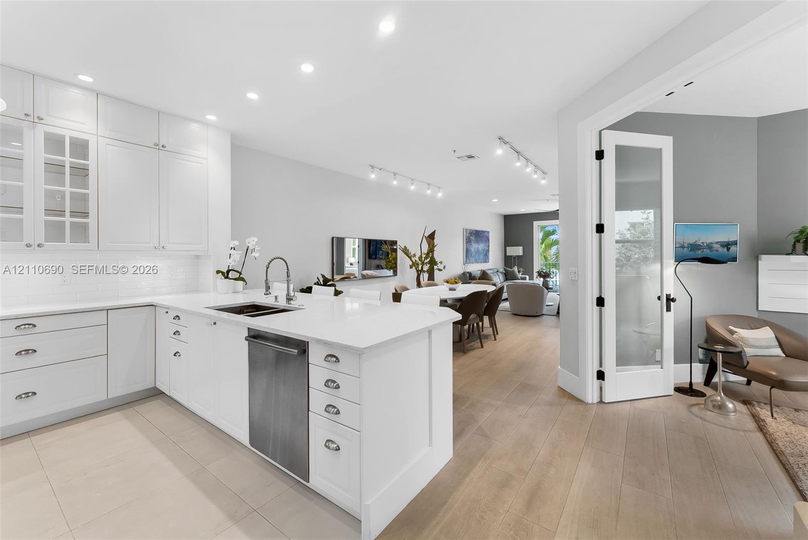 Kitchen featuring white shaker-style cabinetry, quartz countertops, a stainless steel dishwasher, recessed lighting, and wood-finish flooring