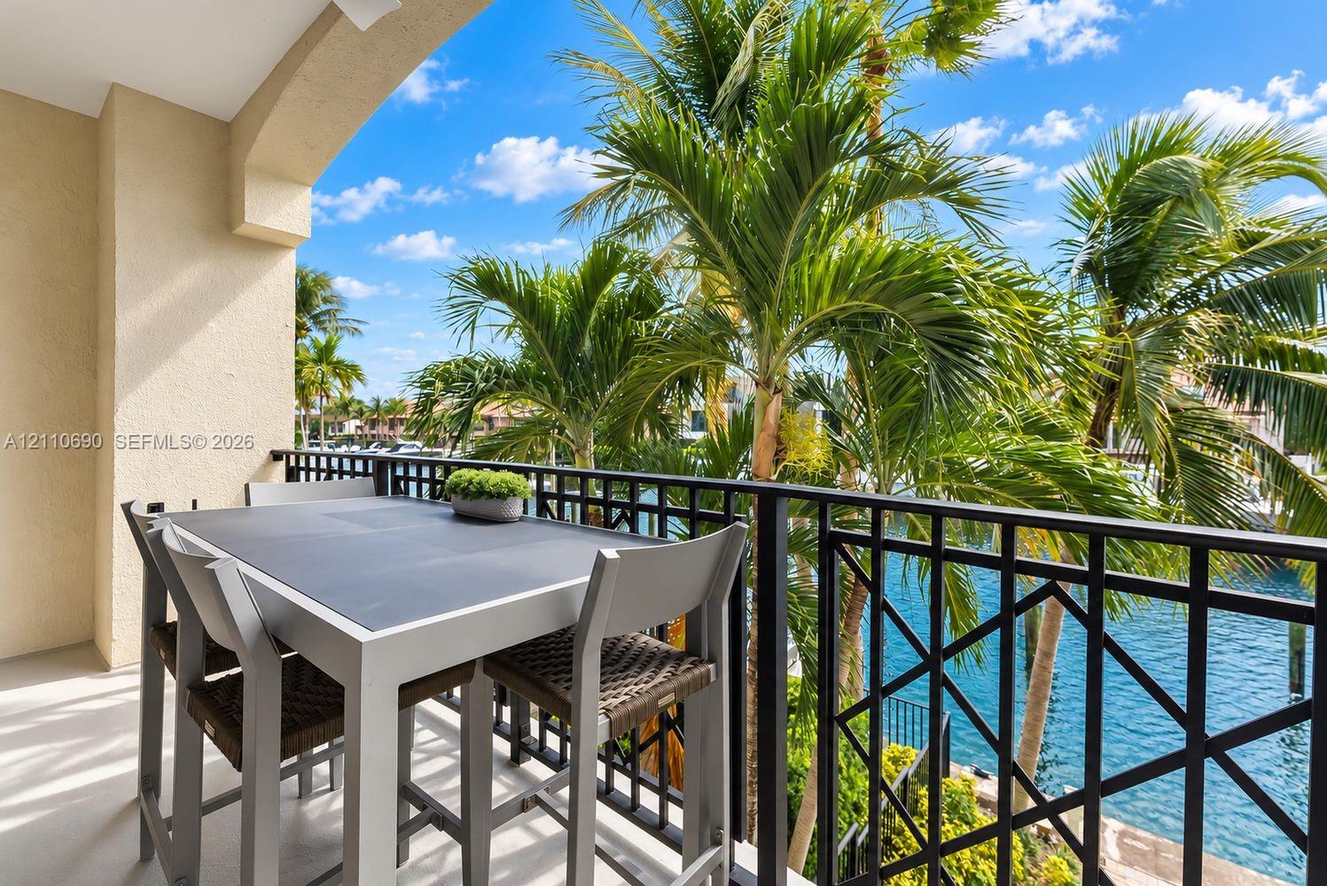 Covered balcony featuring a decorative metal railing, concrete flooring, and water frontage