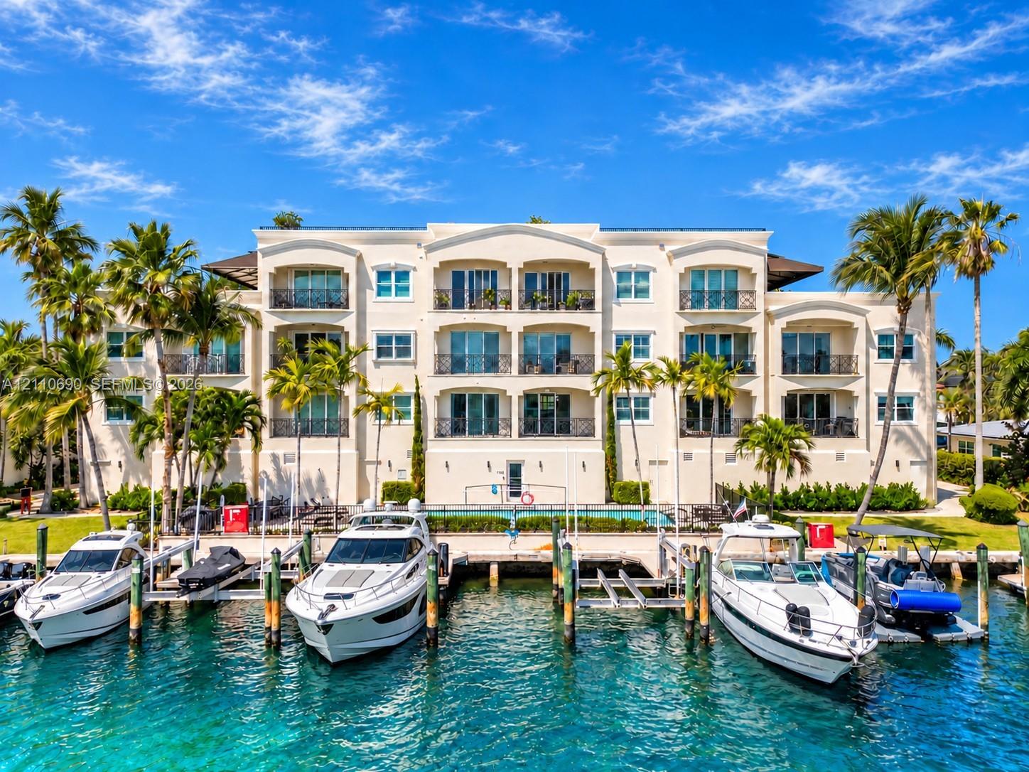 Multi-story building featuring stucco exterior, private recessed balconies with wrought-iron railings, integrated swimming pool, and deep-water boat slips