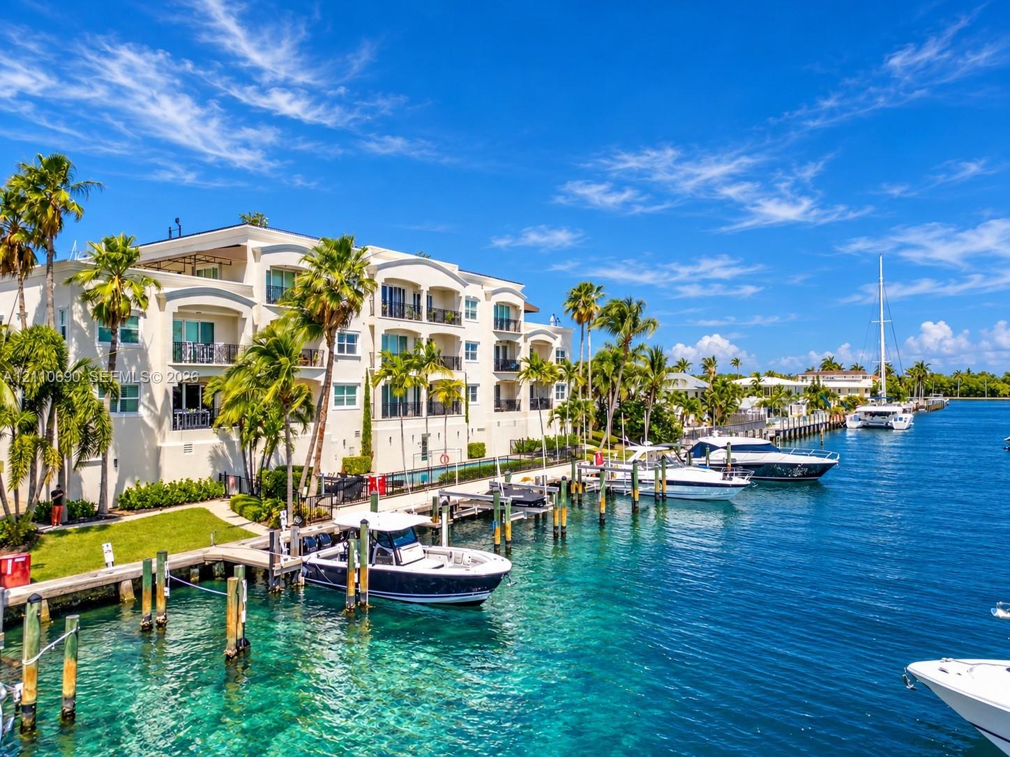 Waterfront residence featuring a three-story white stucco facade with arched windows and multiple balconies Waterfront residence featuring a three-story white stucco facade with arched windows and multiple balconies