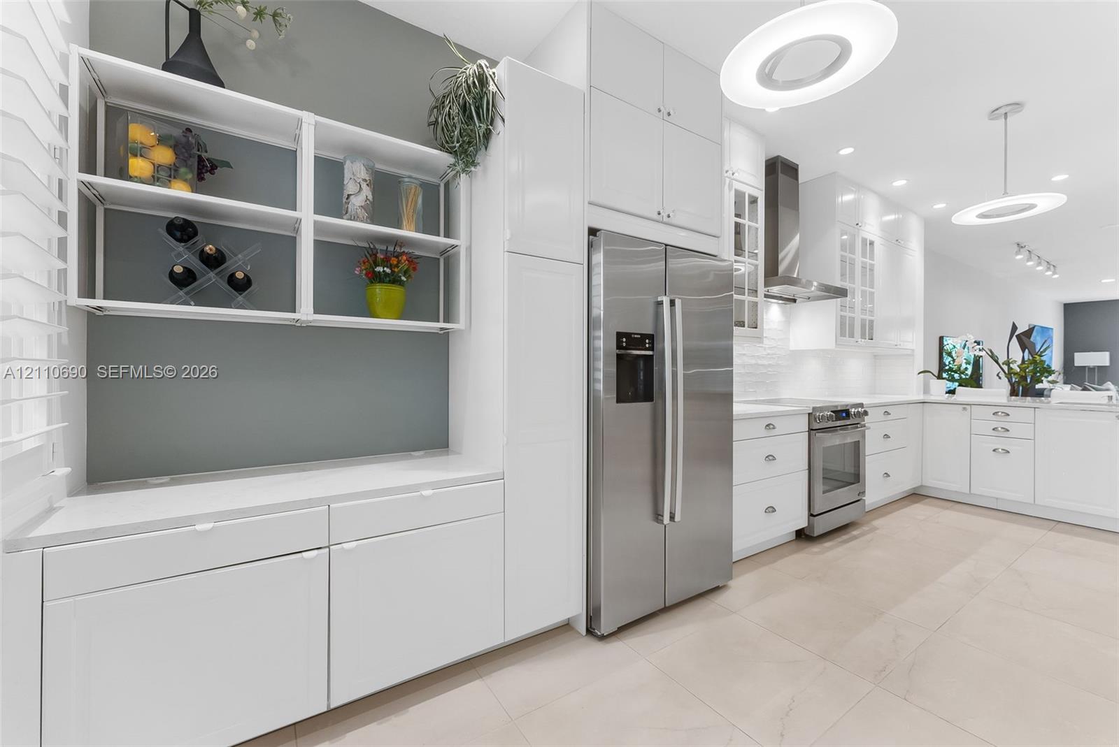 Kitchen featuring white cabinetry, stainless steel appliances, solid surface countertops, tile flooring, and custom wall-mounted shelving
