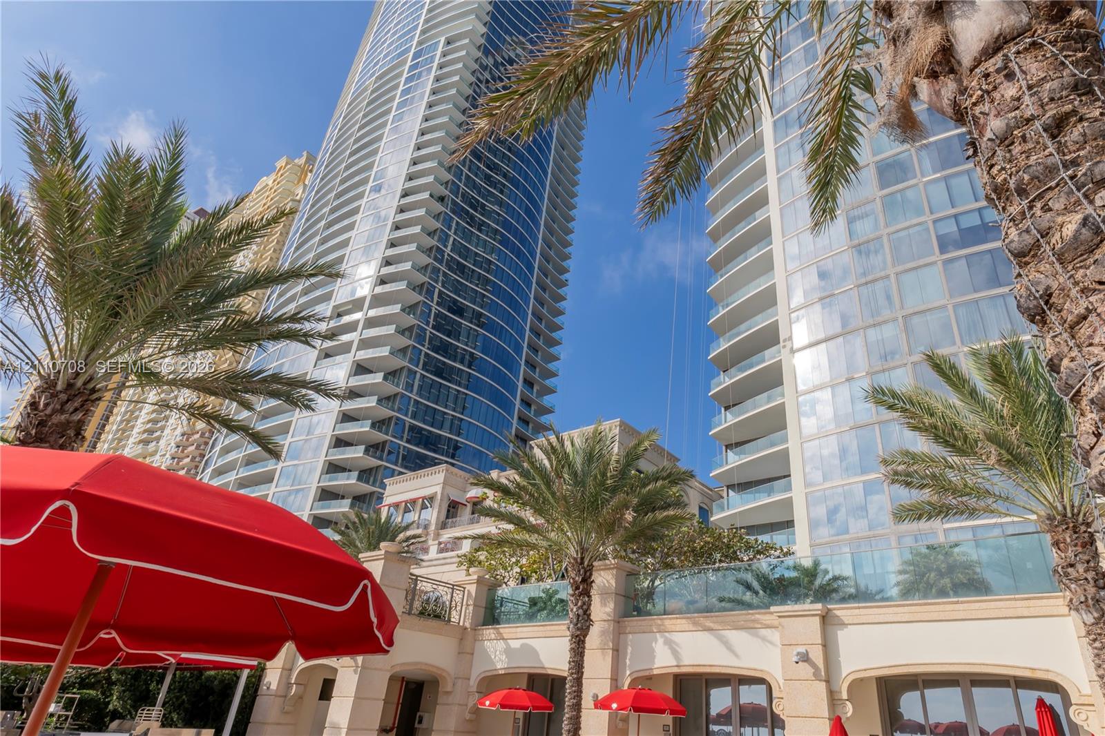 High-rise architectural exterior featuring glass curtain walls, integrated balconies, and stone-finished lower-level facade