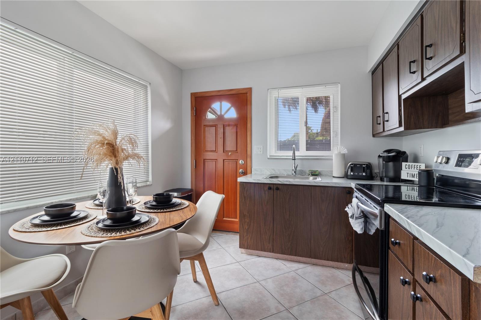 Kitchen featuring wood cabinetry, stone-finish countertops, tile flooring, and a glass-paneled wooden door