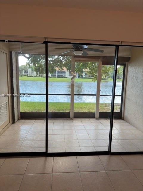 Screened patio with tile flooring and a ceiling fan, featuring a water-facing orientation Screened patio with tile flooring and a ceiling fan, featuring a water-facing orientation
