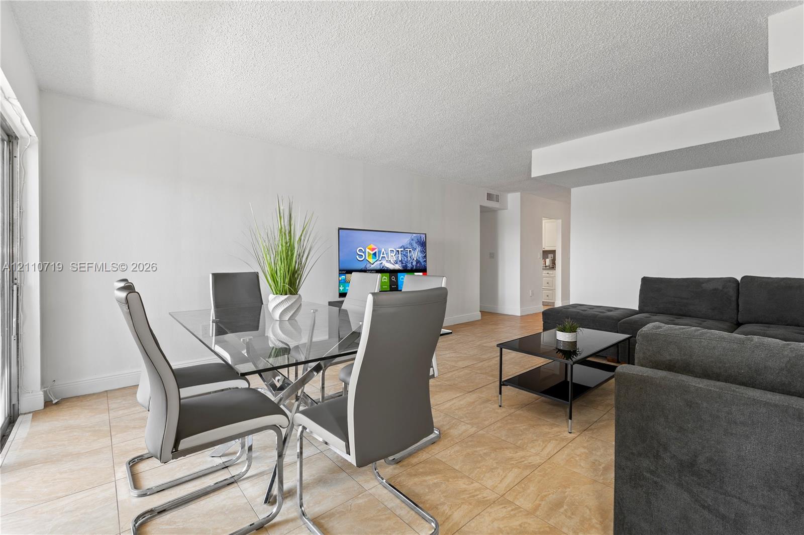 Neutral-toned ceramic tile flooring, clean white walls, and a glass-paneled sliding door