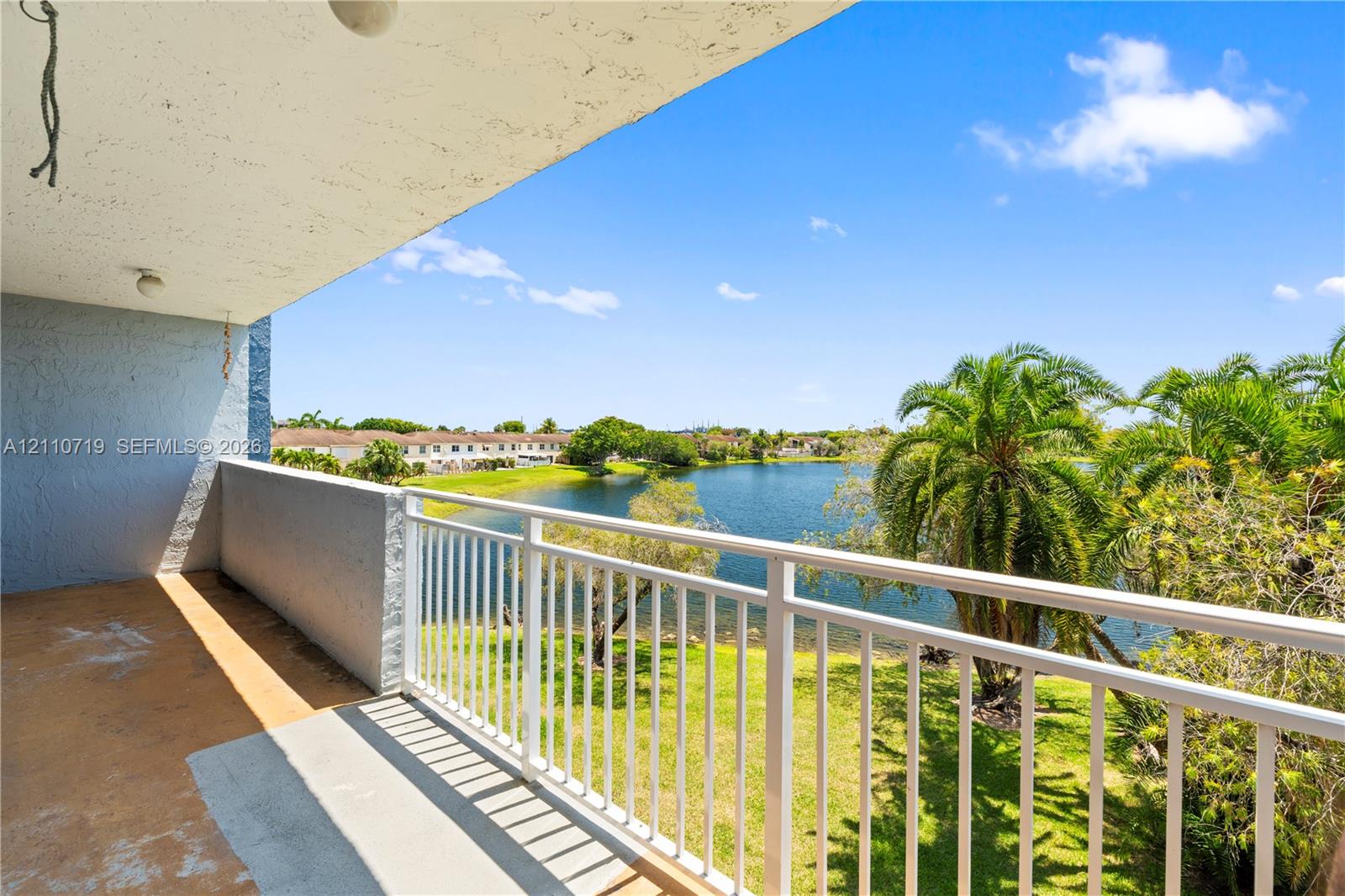 Covered balcony featuring a white metal railing, concrete flooring, and water frontage