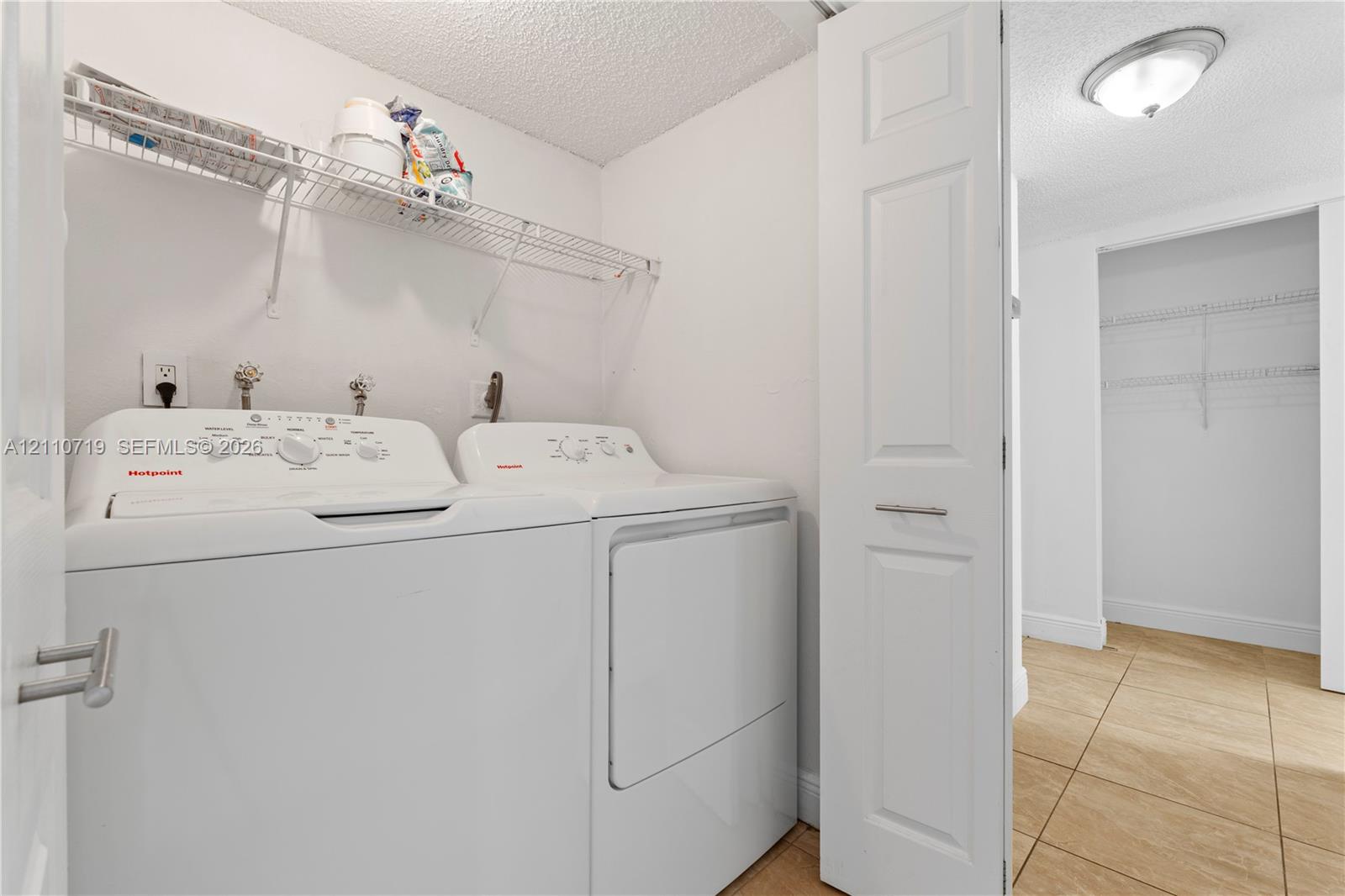 Laundry area featuring tile flooring, white bi-fold door, and wire shelving