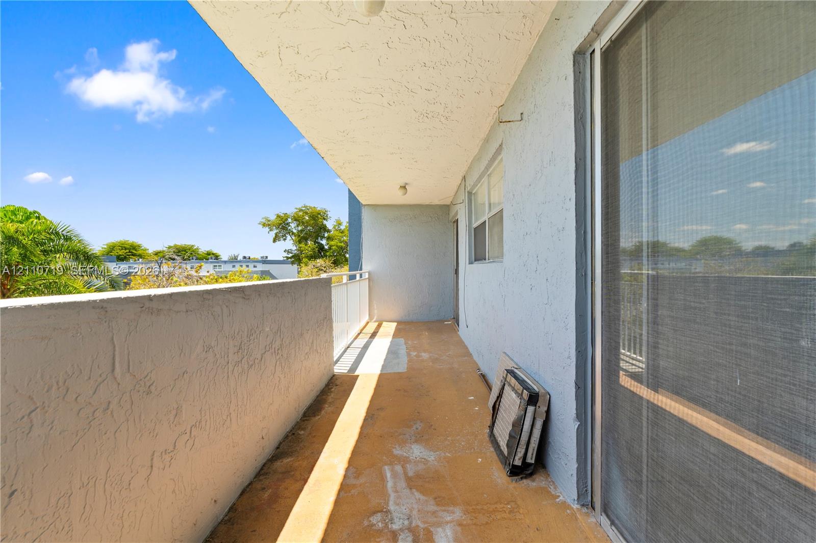 Covered balcony featuring concrete flooring, a solid masonry wall, and a sliding glass door
