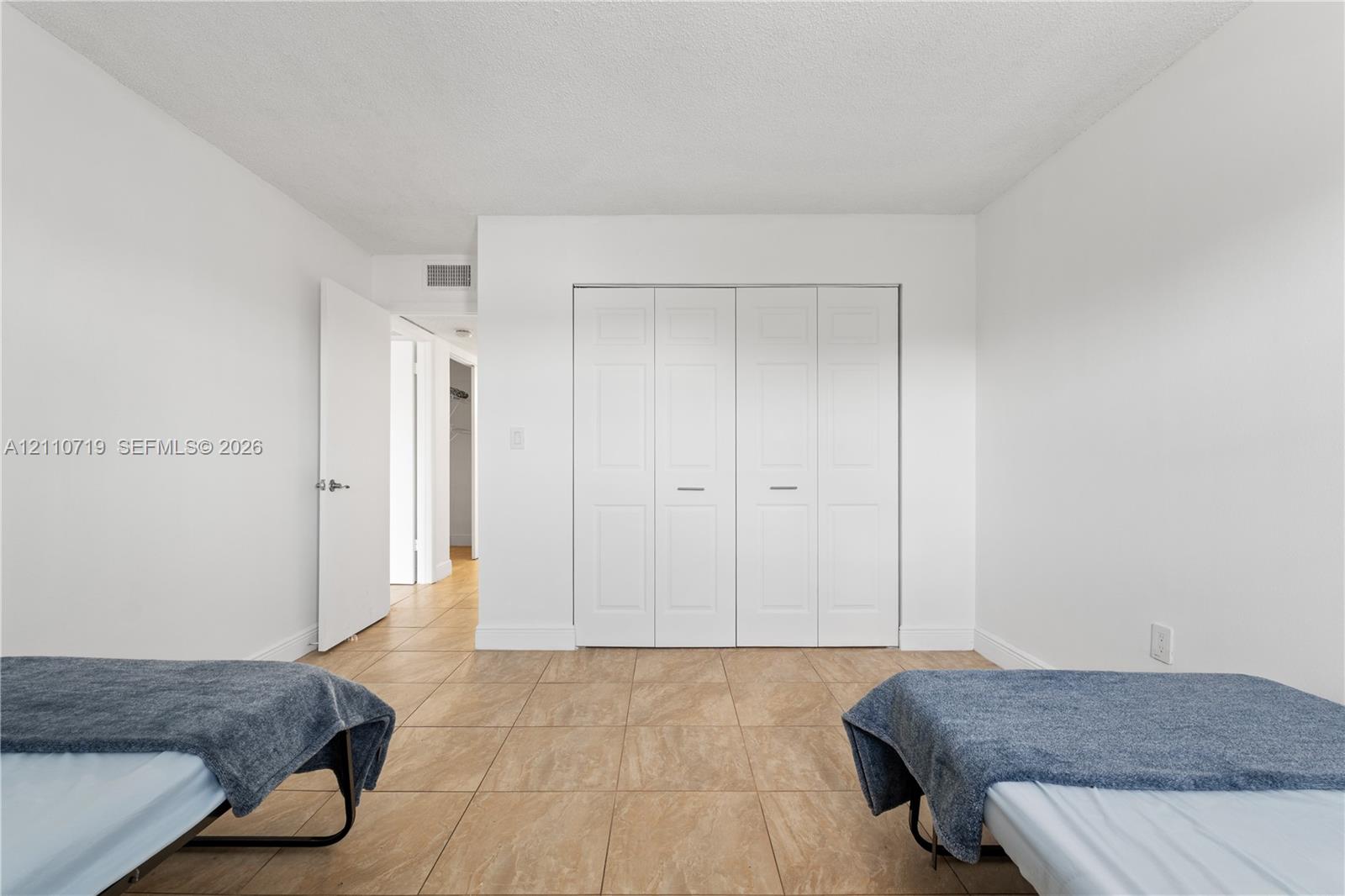 Interior room featuring neutral wall paint, tile flooring, and a large four-panel folding closet door