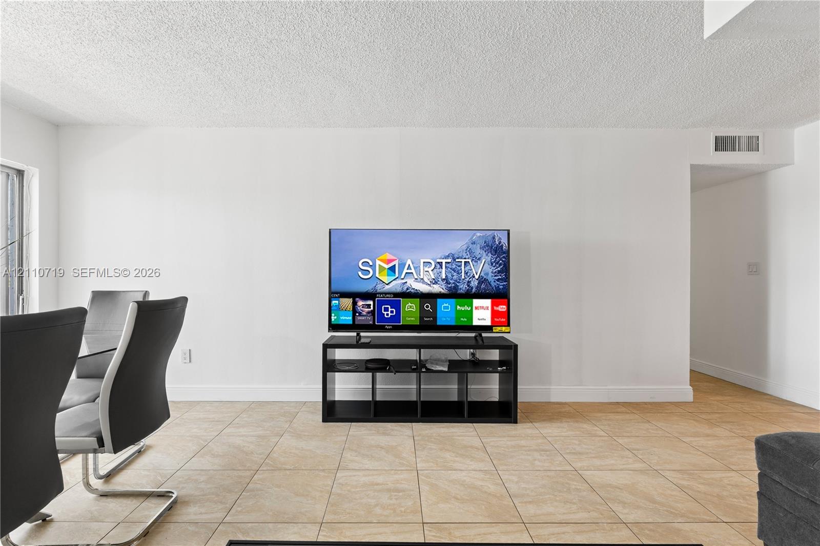 Neutral-toned ceramic tile flooring throughout an open-concept area with smooth white wall finishes