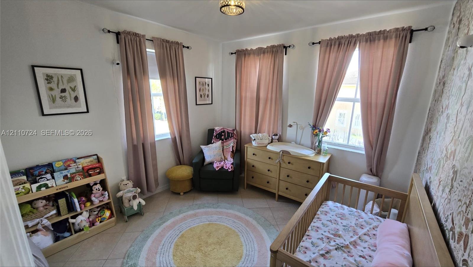 Interior room featuring three double-hung windows, tile flooring, and patterned accent wallpaper