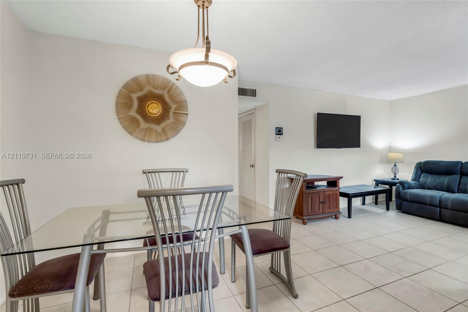 Open-concept interior featuring neutral wall tones, large-format tile flooring, and a multi-arm metal pendant light fixture