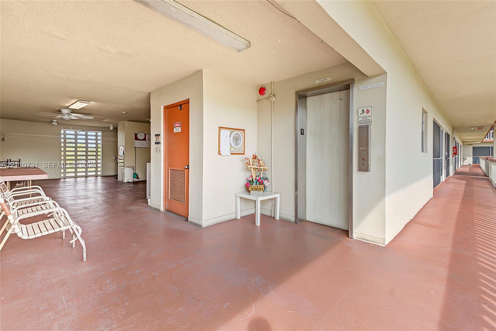 Covered exterior corridor featuring a dedicated elevator, recessed ceiling lighting, and a painted concrete surface