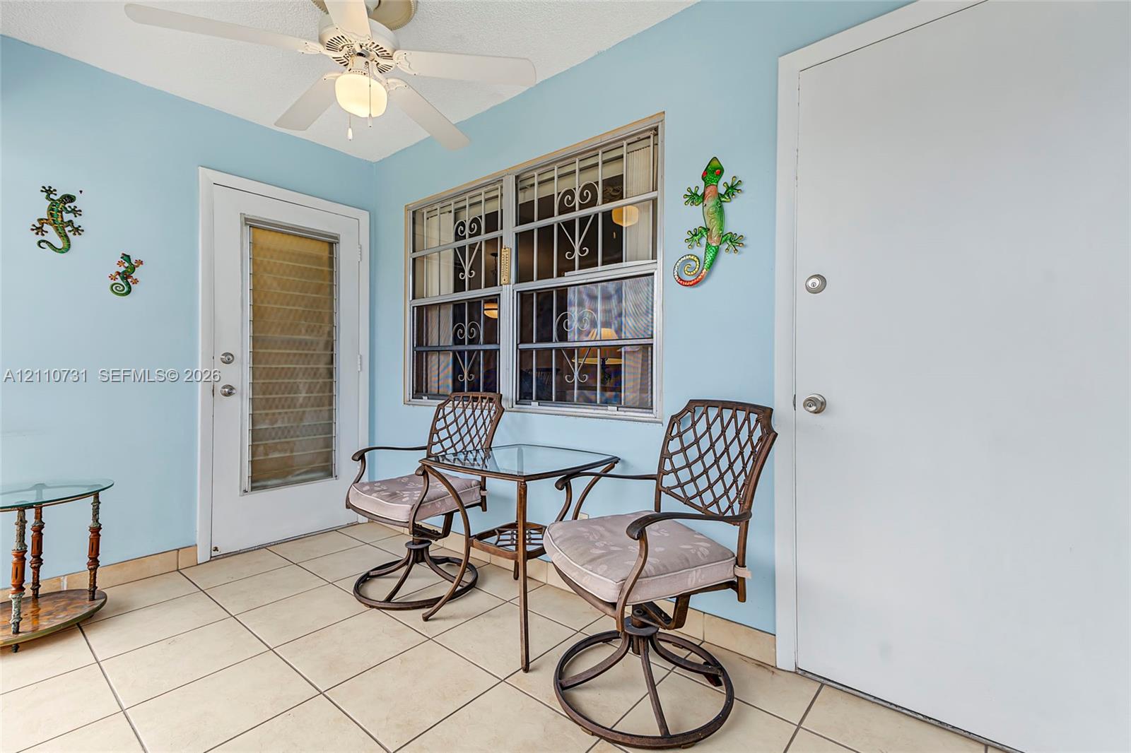 Enclosed porch featuring ceramic tile flooring, a multi-blade ceiling fan, security-screened entry doors, and windows with integrated decorative security grilles