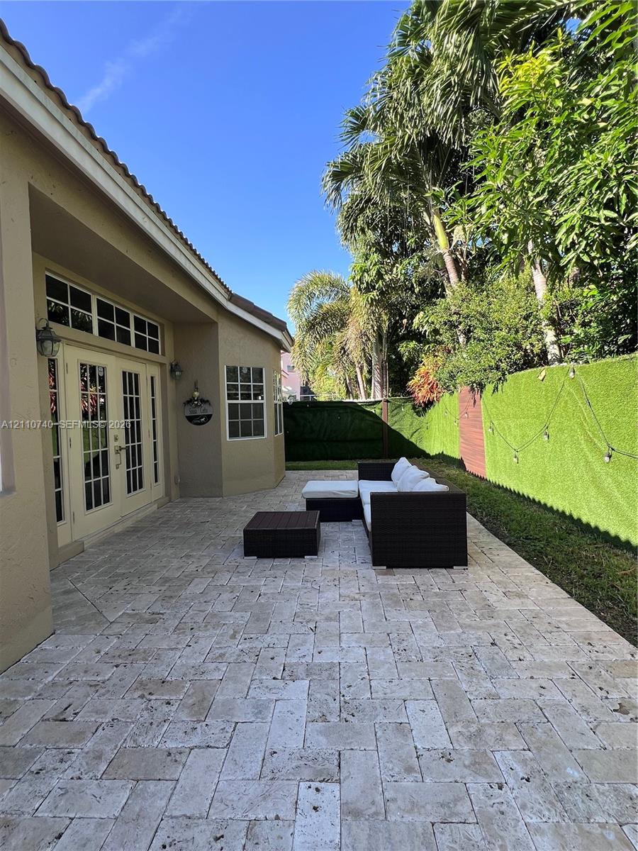 Paver patio featuring a herringbone pattern, double French door entrance with transom windows, and perimeter privacy fencing