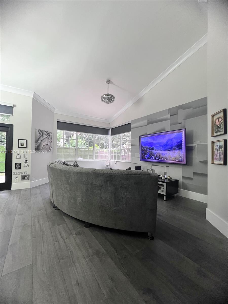 Vaulted ceilings with crown molding, wood-finish flooring, accent wall, multi-pane windows, and recessed lighting