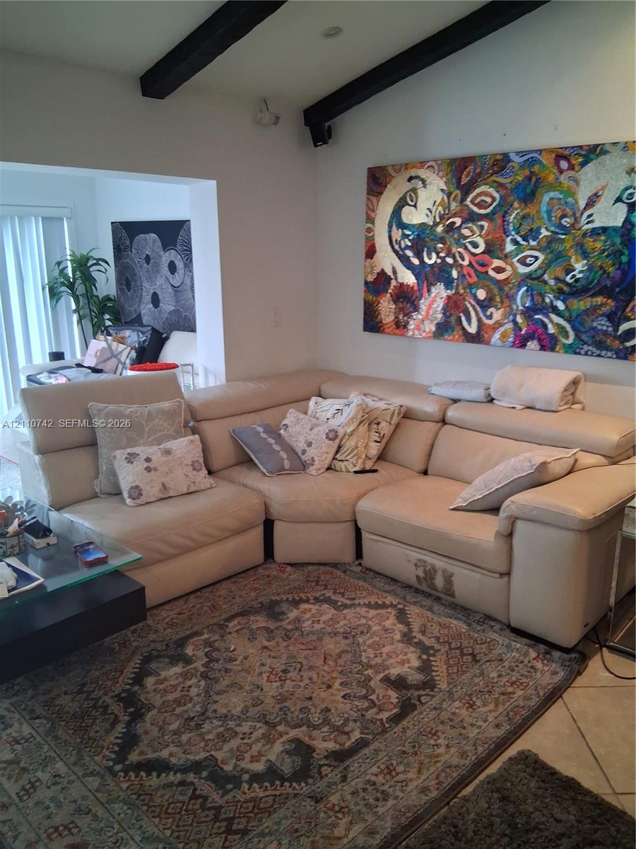 Vaulted ceiling featuring exposed dark-finish structural beams and tile flooring Vaulted ceiling featuring exposed dark-finish structural beams and tile flooring