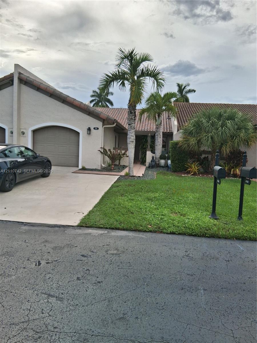 Stucco exterior featuring a concrete tile roof, an arched garage entrance, and a paved driveway Stucco exterior featuring a concrete tile roof, an arched garage entrance, and a paved driveway