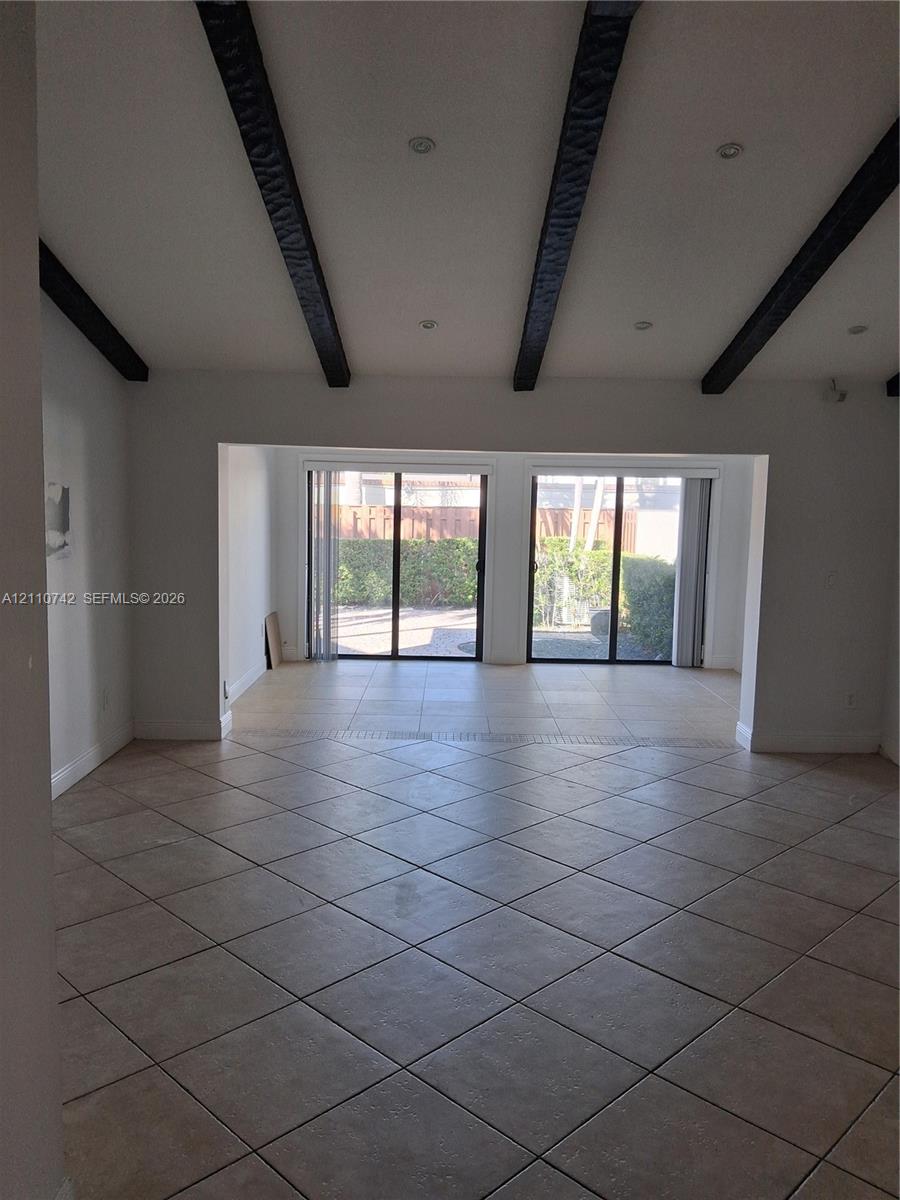 Vaulted ceilings featuring exposed dark-toned beams, recessed lighting, diagonal-set ceramic tile flooring, and dual sliding glass doors Vaulted ceilings featuring exposed dark-toned beams, recessed lighting, diagonal-set ceramic tile flooring, and dual sliding glass doors