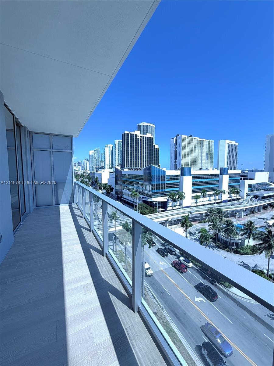 Covered balcony featuring wood-finish flooring and glass panel railings