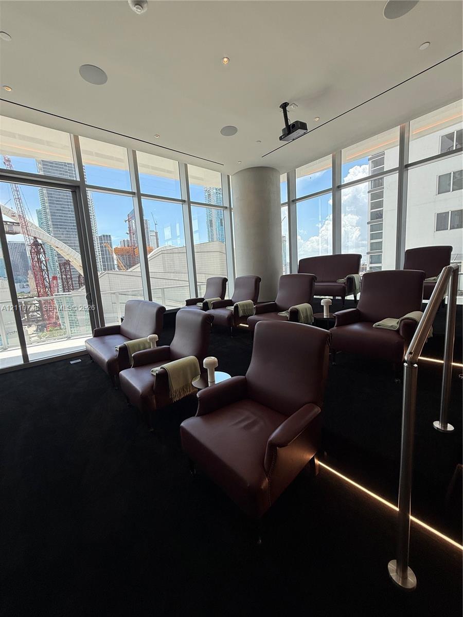 Floor-to-ceiling windows, tiered seating platform with integrated stair lighting, ceiling-mounted projection system, and recessed overhead lighting