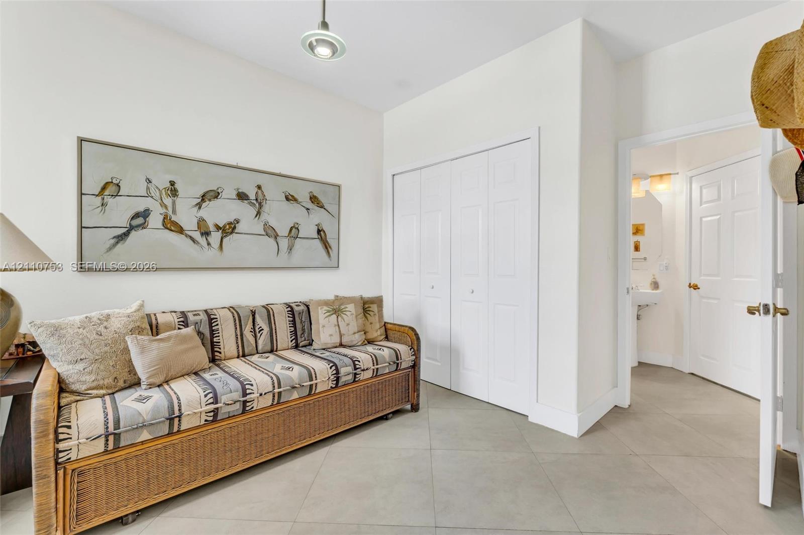 Large-format neutral floor tile, recessed ceiling lighting, and double-panel closet doors with white finish