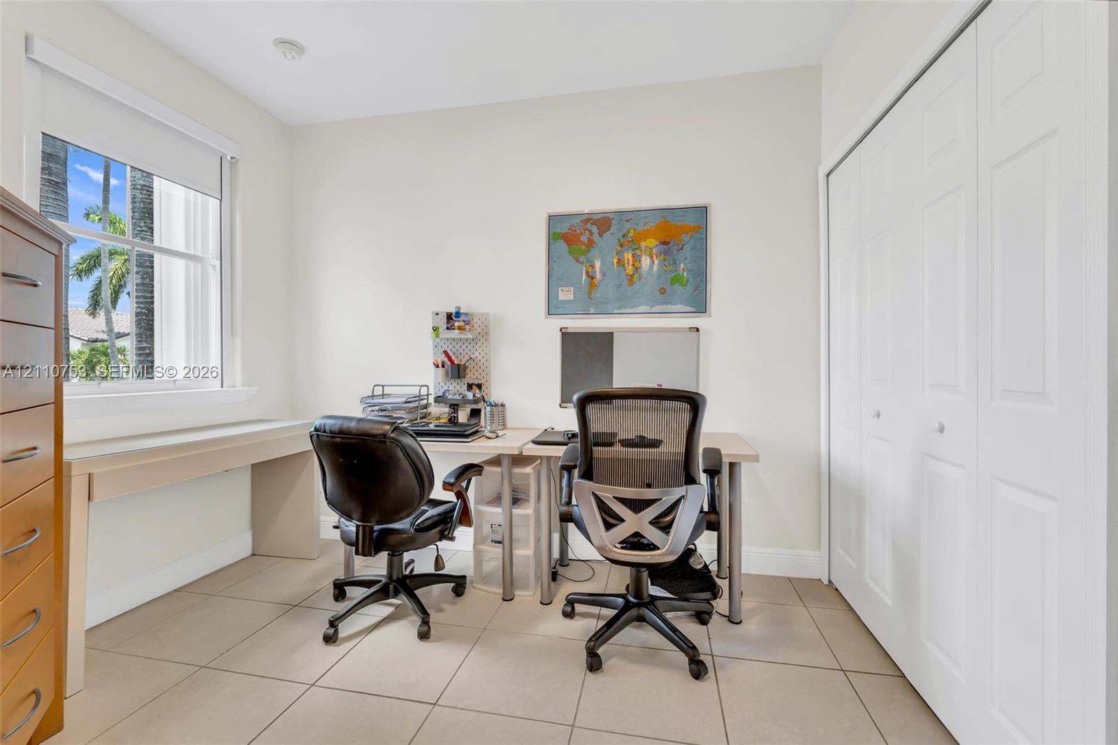 Neutral-toned ceramic tile flooring, single-hung window with roller shade, and white bi-fold closet doors