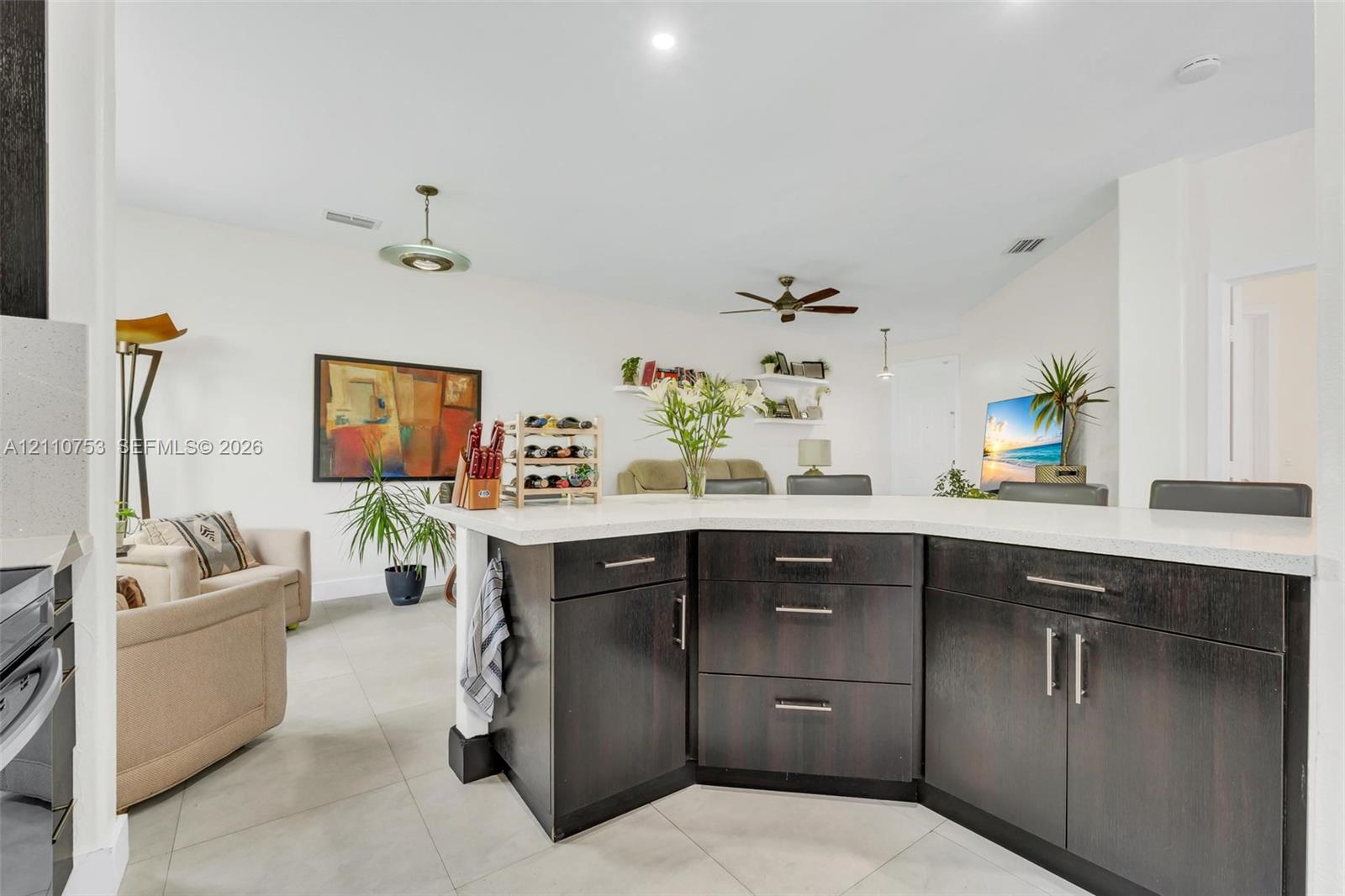Kitchen peninsula featuring dark cabinetry, solid-surface countertop, tile flooring, recessed ceiling lighting, and a ceiling fan