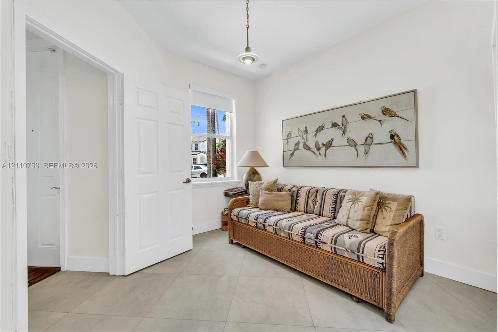 Neutral-toned tile flooring, single-panel interior doors, and a ceiling-mounted pendant light fixture