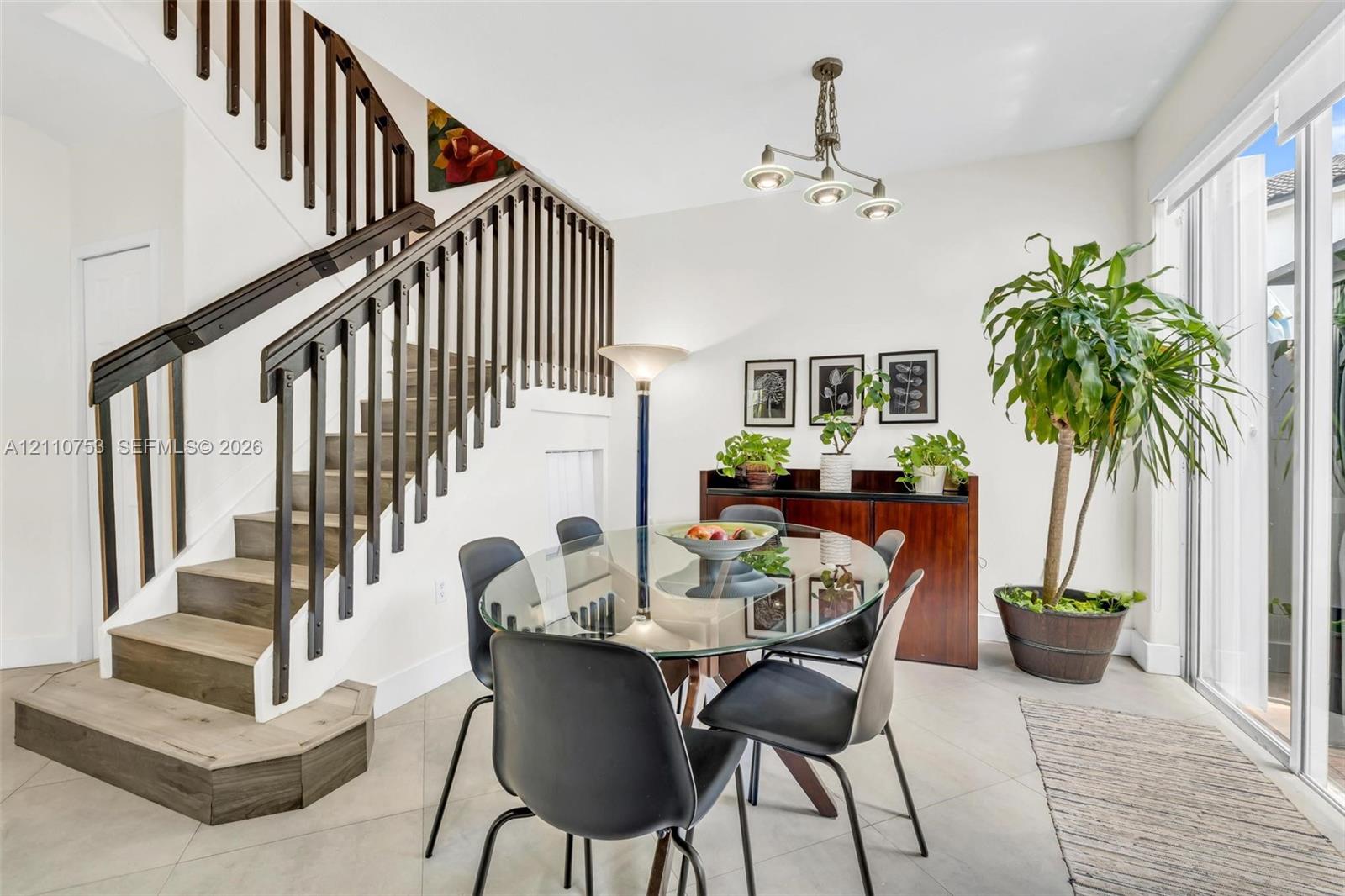 Staircase featuring wood-finish treads and dark-toned balusters, large-format tile flooring, multi-light fixture, and glass sliding doors