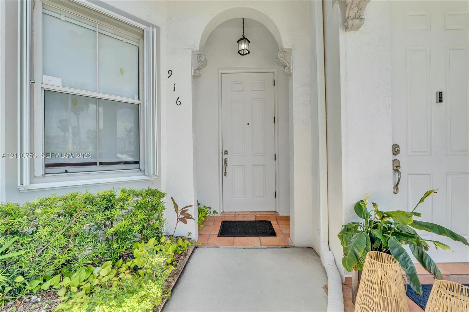 Entrance featuring an arched recessed entry, multi-paneled door, hanging lantern-style light fixture, and tile porch flooring