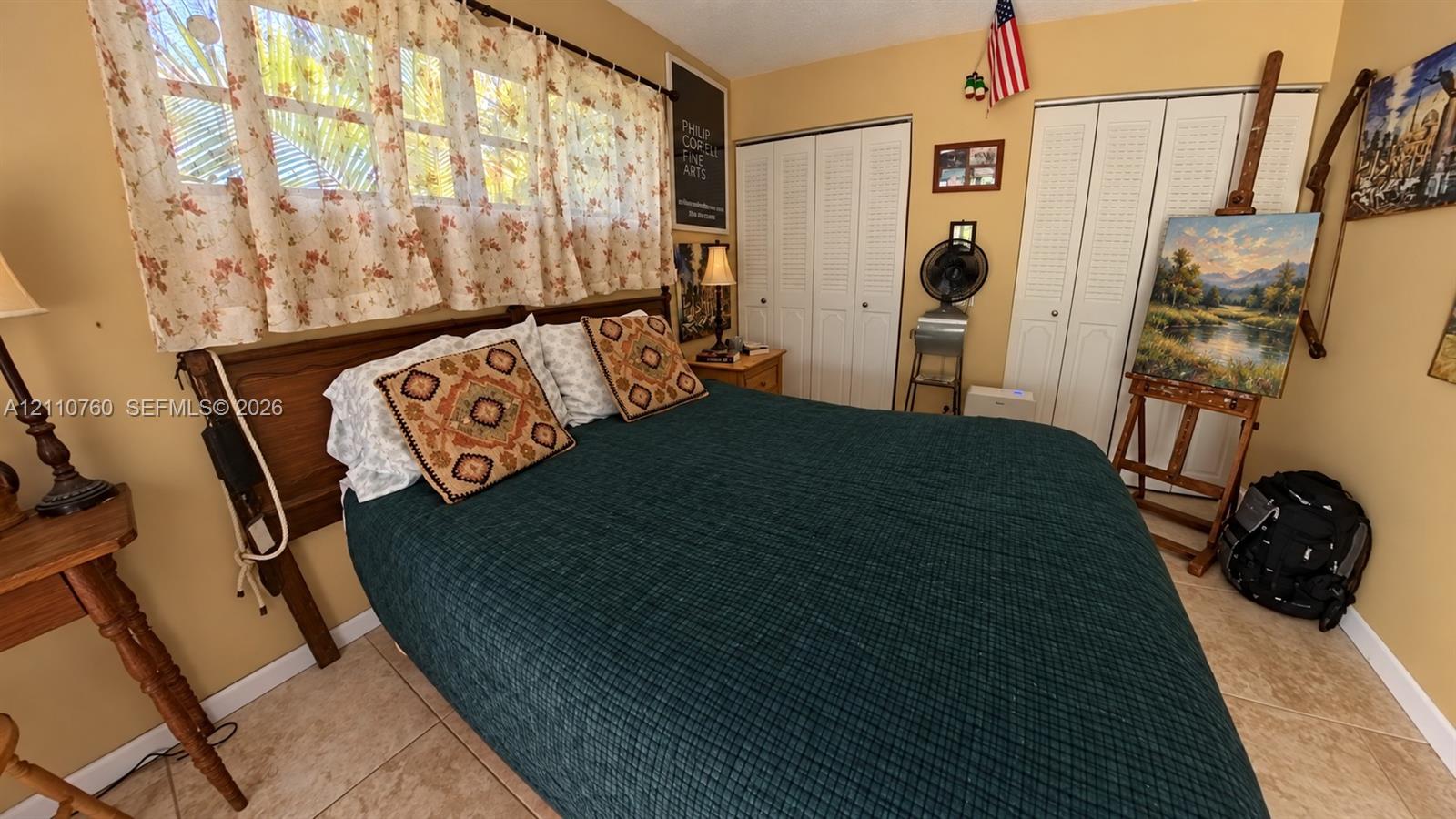 Neutral wall palette, multi-pane window configuration, and dual white louvered-panel closets featuring hard-surface tile flooring