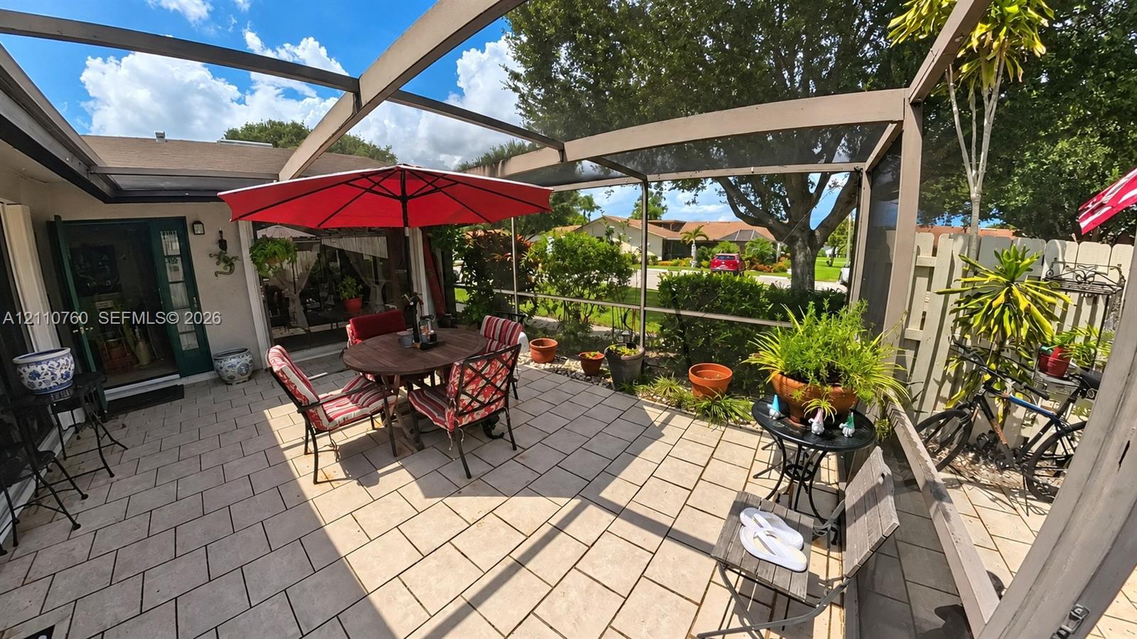 Screened-in outdoor patio featuring paved tile flooring and a covered structure