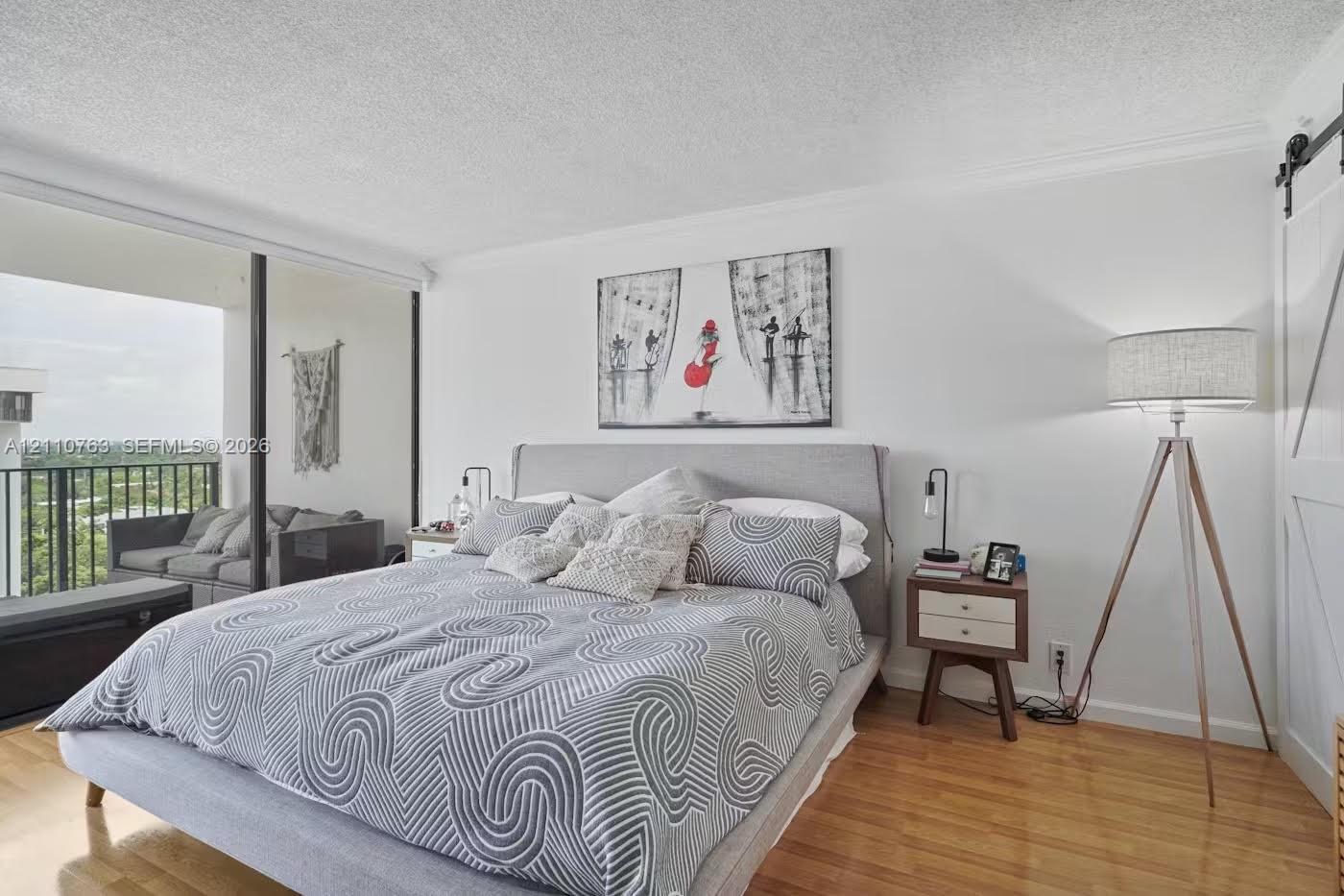Wood-finish flooring, floor-to-ceiling glass sliding doors, private balcony, and white sliding barn door Wood-finish flooring, floor-to-ceiling glass sliding doors, private balcony, and white sliding barn door