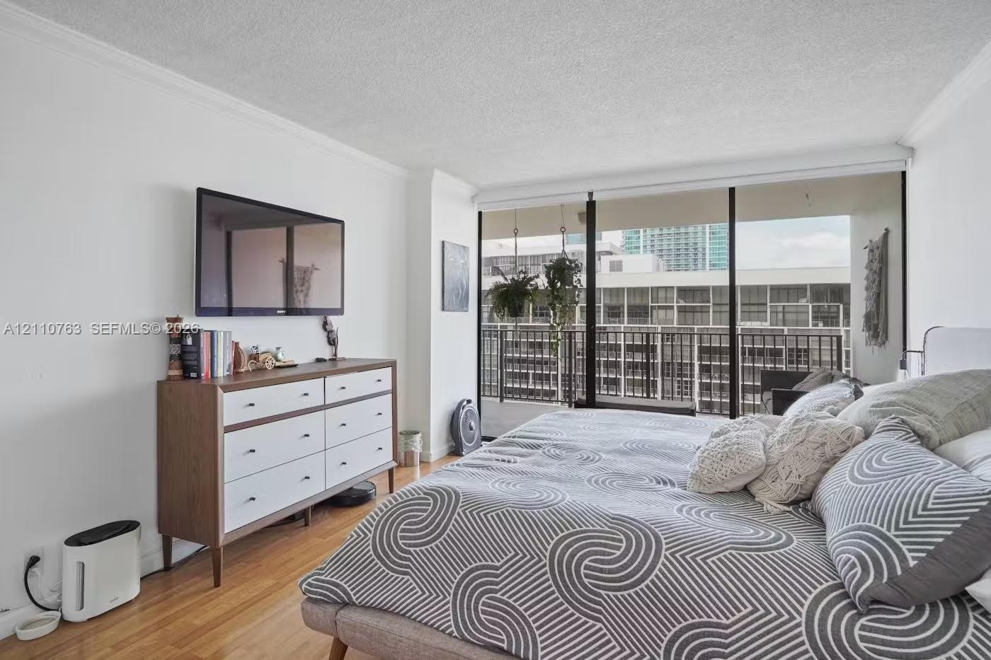 Floor-to-ceiling windows featuring access to a private balcony, wood-finish flooring, and crown molding Floor-to-ceiling windows featuring access to a private balcony, wood-finish flooring, and crown molding