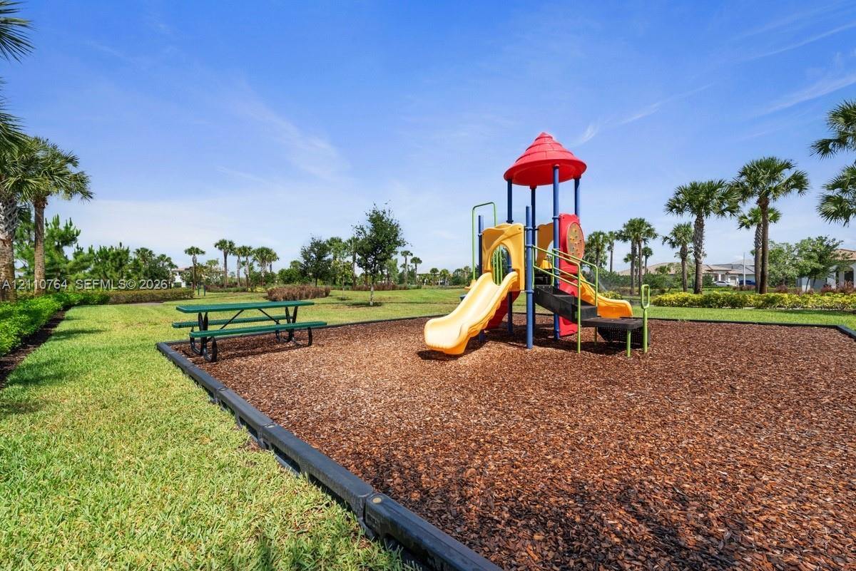 Outdoor play structure featuring multiple slides, integrated stairs, and a circular roof canopy, situated within a mulched border area