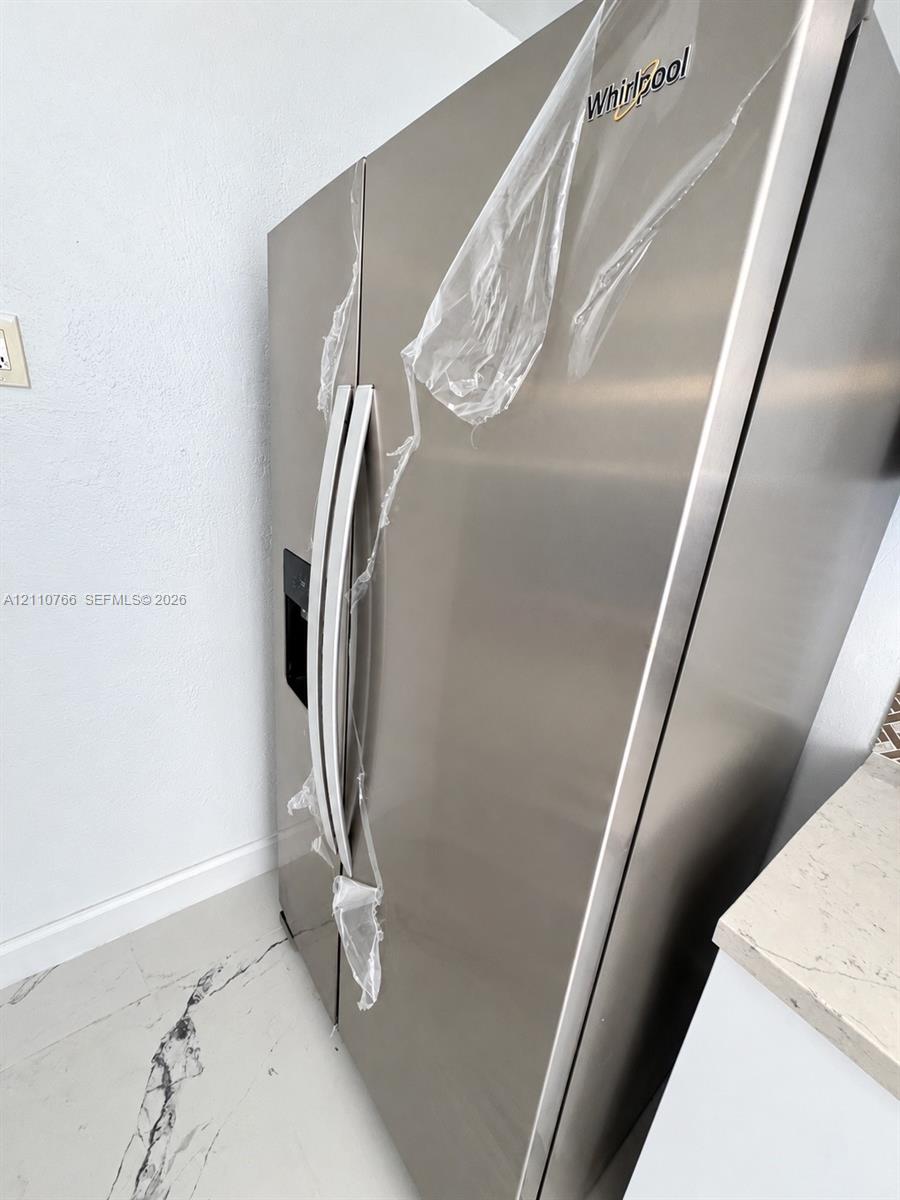Stainless steel Whirlpool refrigerator featuring an integrated door water and ice dispenser