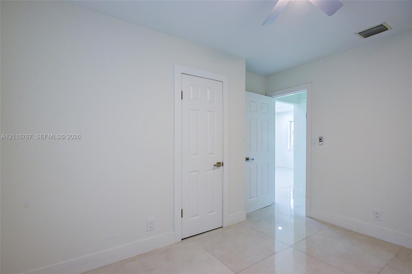 Polished tile flooring, six-panel interior doors, and a ceiling-mounted fan fixture