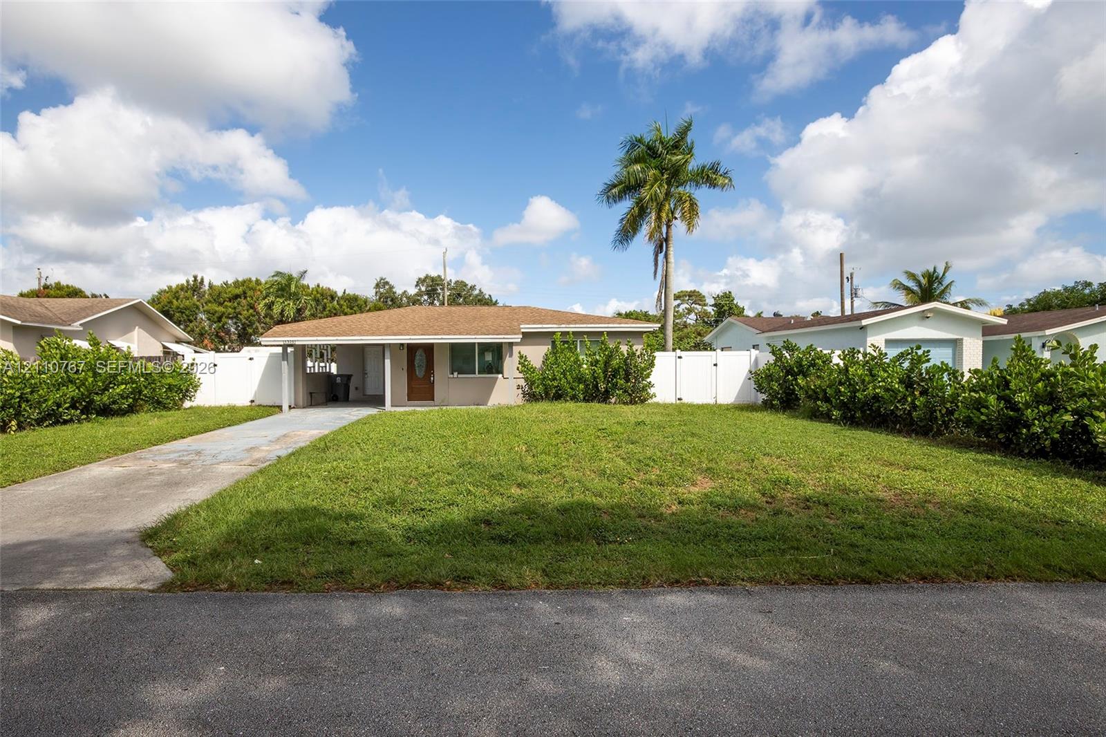 Single-story residence featuring a low-slope roof, covered entryway, concrete driveway, and full-perimeter vinyl privacy fencing