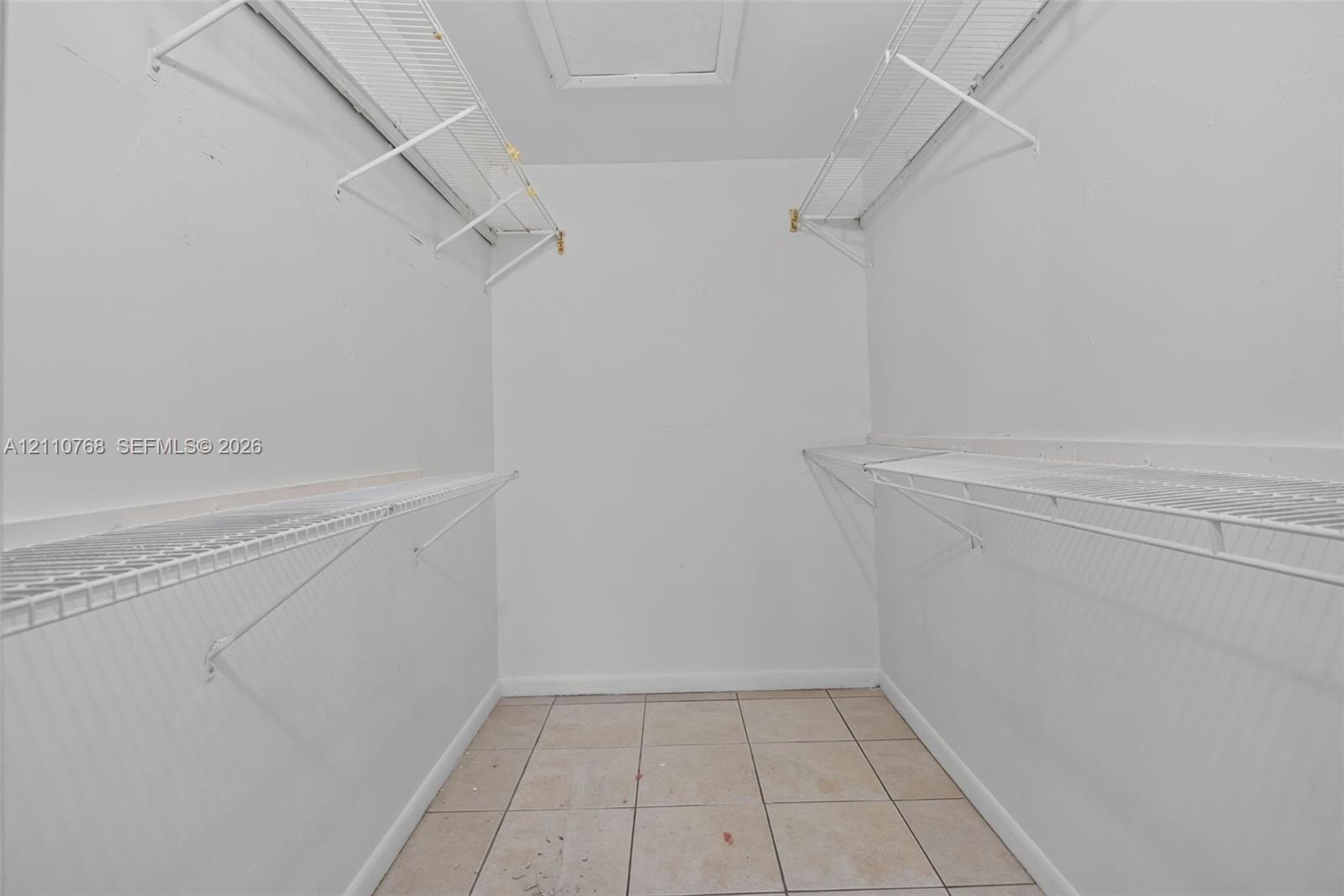 Walk-in storage space featuring ceramic tile flooring and multi-level white wire shelving