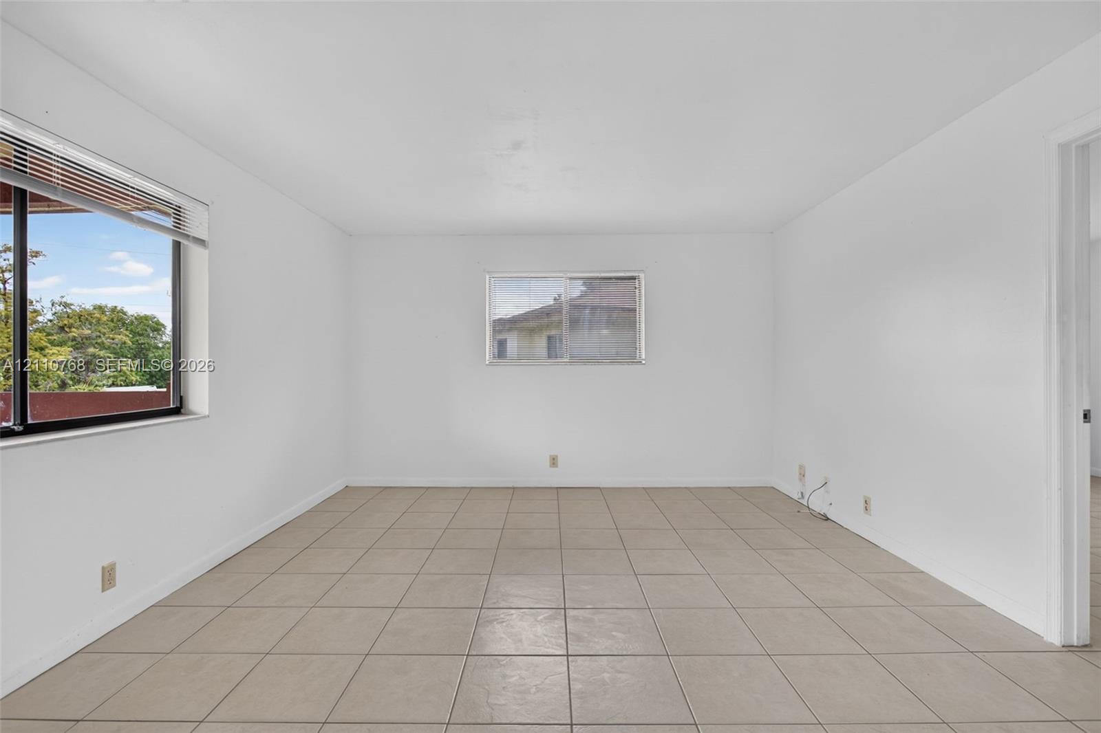 Neutral-toned ceramic tile flooring, clean white wall finishes, and multiple windows providing natural light
